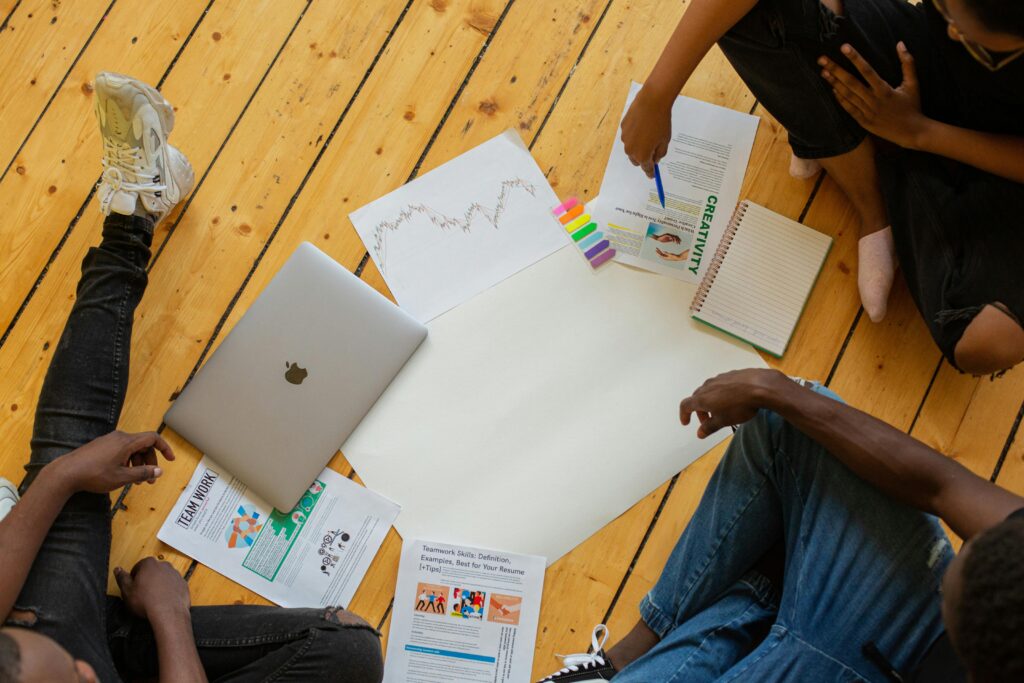 pexels-photo-9489398-9489398 Overhead view of diverse team collaborating with documents and laptop in a meeting.